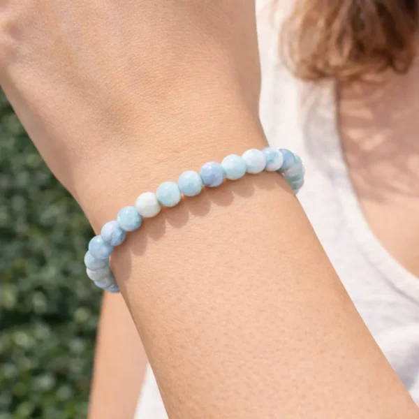 Bracelet en Larimar naturel porté au poignet, perles bleues et blanches