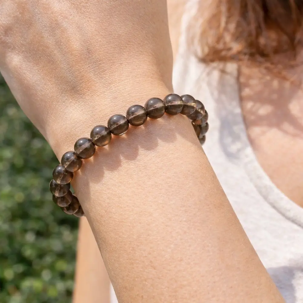 Bracelet en Quartz Fumé naturel porté au poignet, révélant la transparence des pierres et le soin apporté à la confection artisanale.