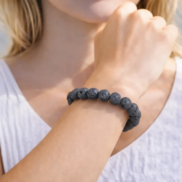 Bracelet en Pierre de Lave naturelle porté au poignet, perles noires mates et poreuses issues du basalte volcanique, montage artisanal.