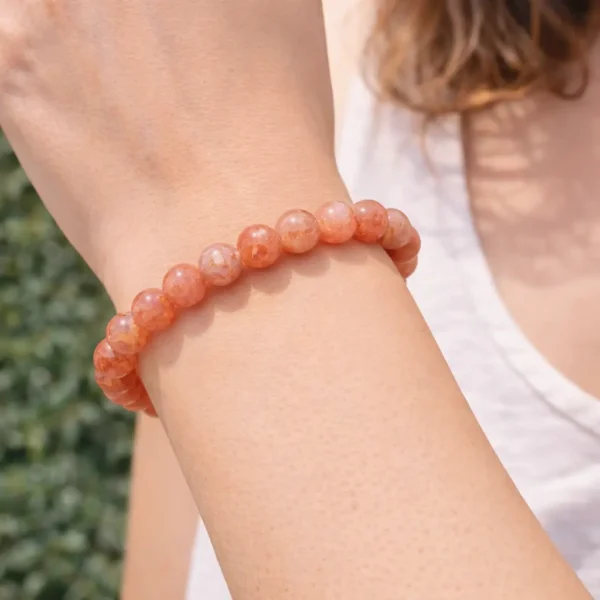 Bracelet en perles de pierre de soleil orange scintillante porté au poignet